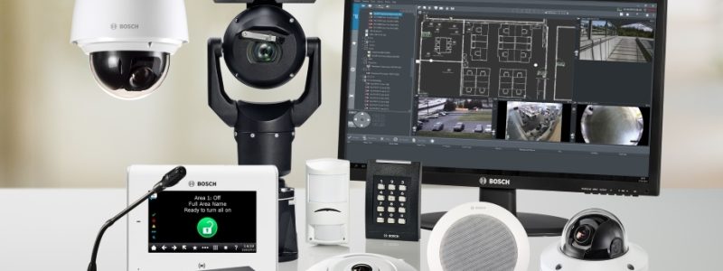 Verkada Installers A collection of Bosch security equipment including cameras, a control panel, monitor displaying surveillance feeds, microphones, speaker, and remote controls arranged on a white surface by Jendy Physical Security.